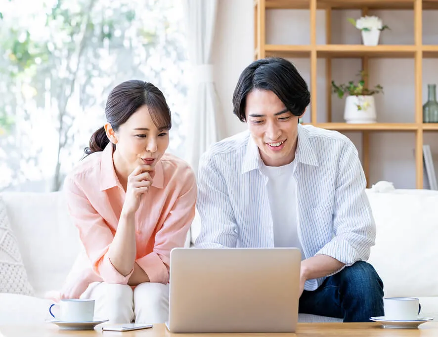 カップルがパソコンを眺めながら相談し合う様子